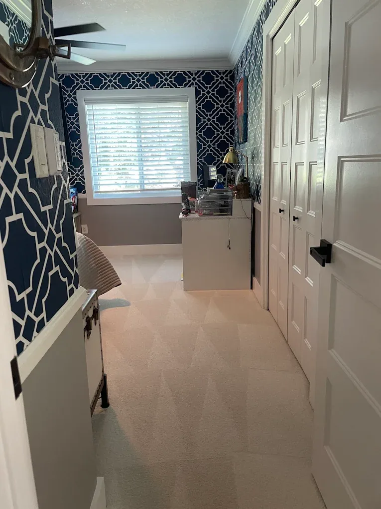 doorway view cream carpet white desk navy wallpaper